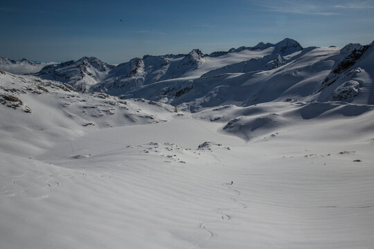 A skier and his perfect tracks on a sunny day in the wide open terrain of the Spearhead Traverse out of Whistler, British Columbia, Canada.