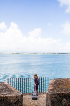 A young woman rolls her luggage to an overlook in Old San Juan, Puerto Rico