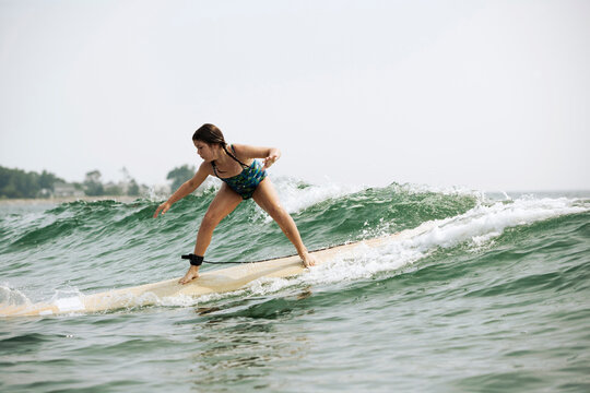 A young girls balances on her surfboard while catching a wave.