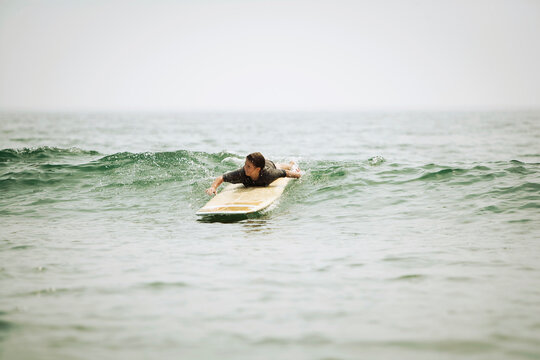 A young girl paddles to catch a wave surfing