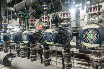 Huge industrial water pump and air handling unit in the ventilation plant room with ductworks and insulated pipelines