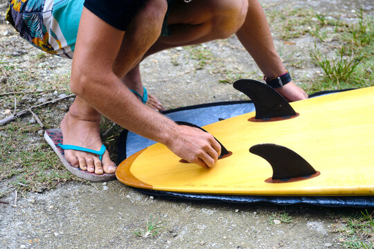 Young man preparing surfboard, Batukaras, Java, Indonesia