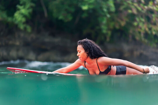 Female surfer paddling surfboard, Batukaras, Java, Indonesia