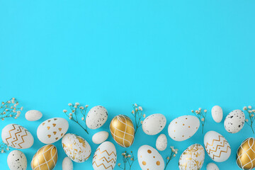 Hello Easter concept. Flat lay photo of white and gold eggs with gypsophila flowers on pastel blue background with empty space. Easter invitation card idea.