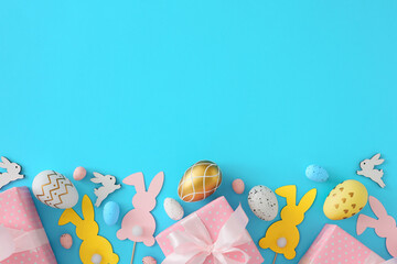 Fototapeta na wymiar Easter decor concept. Top view photo of white and gold eggs with cute rabbits and pink gift boxes on pastel blue background with blank space. Holiday card idea.