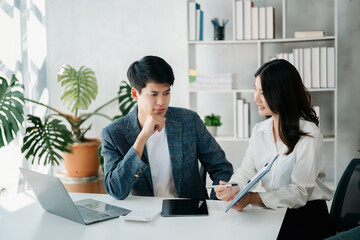 Businesswomen work and discuss their business plans. A Human employee explains and shows her colleague the results paper in modern office..