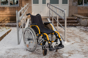 Fototapeta na wymiar Empty wheelchair in the hospital on the ramp. Wheelchair close-up. Children's wheelchair