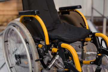 Fototapeta na wymiar Empty wheelchair in the hospital on the ramp. Wheelchair close-up. Children's wheelchair