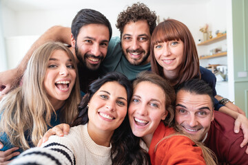 Fototapeta premium A group of friends taking a selfie at home. They are all gathered together, with big smiles on their faces .