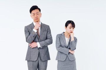 疑問を感じるポーズをするスーツ姿の男女