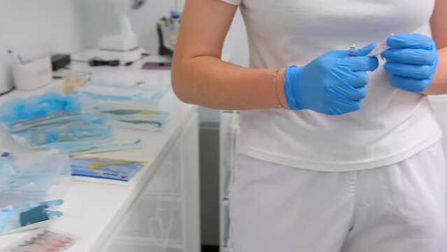 Portrait of a doctor in mask with a syringe in hand. Insulin syringe for anesthesia nurse unpacks Global vaccination. Doctor hand takes vaccine liquid bottle from table for injection. Insulin syringe
