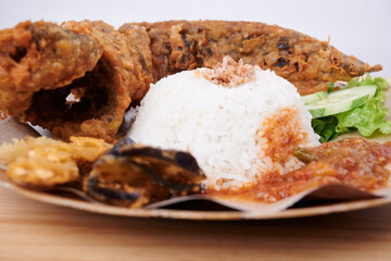 Fried Catfish with Spicy Sauce, rice and vegetables on a plate (Pecel Lele)