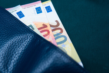 euro banknotes in a wallet on a green background. Concept showing the European economy