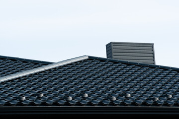 Black corrugated metal profile roof installed on a modern house. Roof of house with chimney