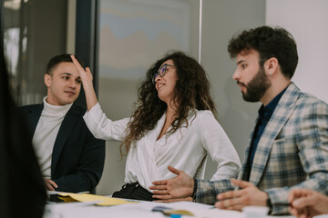 A lovely businesswoman with curly hair is angry and happy at the same time. She is smiling and yelling to her colleagues