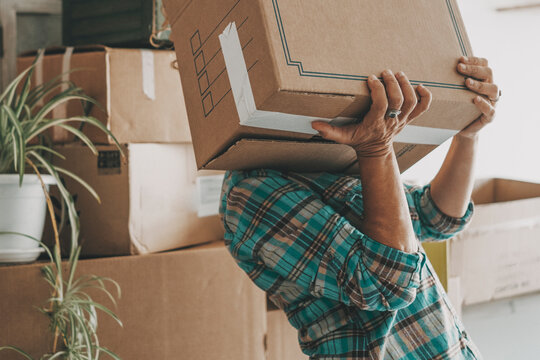 One woman lifting up heavy cardboard box during relocation moving house activity alone. Mortgage. New beginnings adventure female people single lifestyle. Changing life. Home indoors lifestyle people
