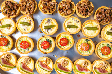 Flat lay photo of canape set cooked in bakery on metal tray. Big group of delicious snacks prepared for wine party in restaurant kitchen