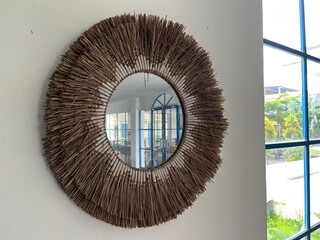 An unique round mirror with bohemian style and rattan frame on the wall for interior decoration.