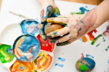 Happy Easter. 3 years boy painting Easter eggs. Religious holiday. Early education and artistic pre-school activities.
