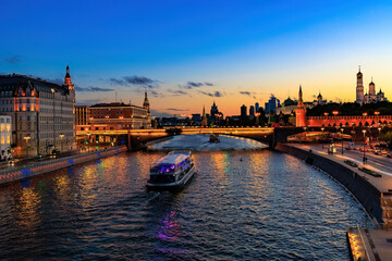 cityscape of Moscow river scenery. Tourboat sails on the river in evening. Moscow Kremlin and Sofiyskaya embankment at night