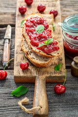 Sandwich with cherries jam on wooden board.