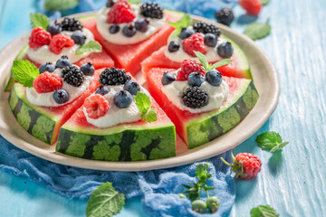 Sweet watermelon pizza with berries, whipped cream and mint leaves.