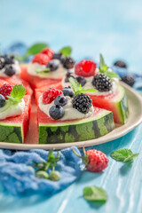 Fresh watermelon pizza with berries, whipped cream and mint leaves.