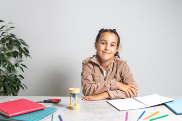 Smart small Caucasian girl child sit at table at home write in exercise book prepare homework for school. education concept.