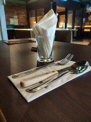Close up shot of a fork and knife on a wooden table, on a napkin