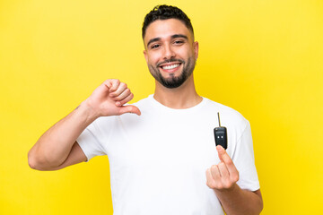 Young Arab man holding car keys isolated on yellow background proud and self-satisfied