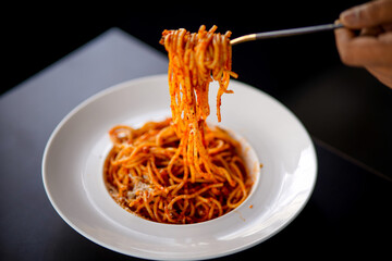 Spaghetti on a fork. Girl use fork with spaghetti. Pasta with red sauce. Stock photo