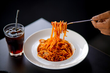 Spaghetti on a fork. Girl use fork with spaghetti. Pasta with red sauce. Stock photo