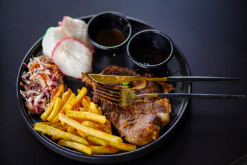 Grilled steak with French fries and vegetables on the plate on black background. stock photo