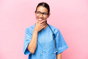 Young nurse Colombian woman isolated on pink background having doubts and with confuse face expression