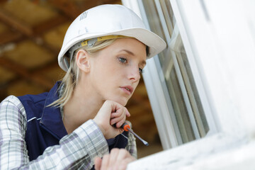 professional female worker holding screwdriver by open windows