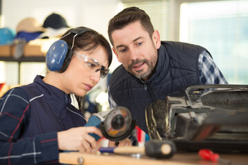 tradeswoman learning to use angle grinder to cut metal