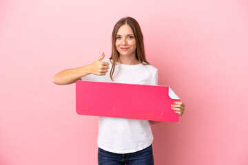 Young Lithuanian woman isolated on pink background holding an empty placard with thumb up