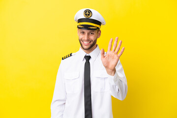 Airplane caucasian pilot isolated on yellow background saluting with hand with happy expression