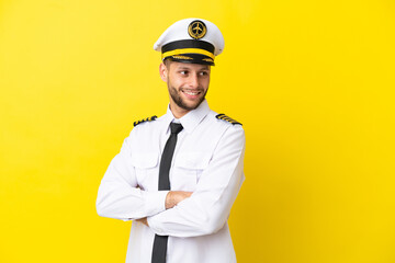 Airplane caucasian pilot isolated on yellow background with arms crossed and happy