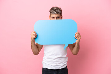 Young handsome caucasian man isolated on pink background holding an empty speech bubble hiding...