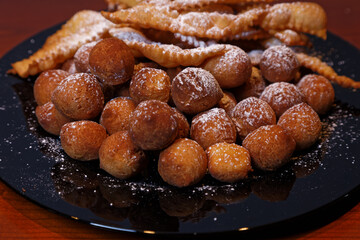 Onbaked castagnole and Frappe or chiacchiere typical Italian carnival fritters dusted with powdered sugar. Biscuits with sugar for the carnival of Venice. Traditional sweet pastries