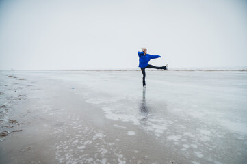 Caucasian woman in a blue sweater skating on a frozen lake. 