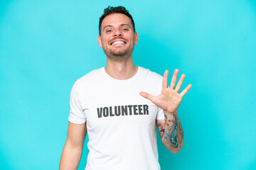 Young volunteer caucasian man isolated on blue background counting five with fingers