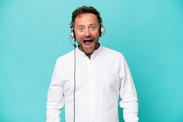 Fototapeta premium Telemarketer caucasian man working with a headset isolated on blue background with surprise facial expression