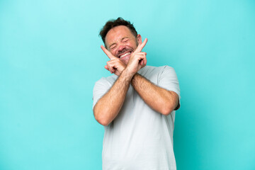 Middle age caucasian man isolated on blue background smiling and showing victory sign