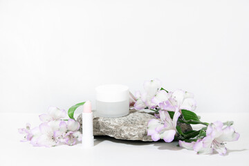 Fototapeta na wymiar White cosmetics background. Cosmetic bottle containers with flowers plant . Blank label package for branding mock-up, with hard shadows. Natural organic beauty product concept. Banner
