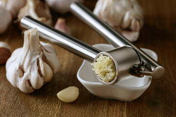 Fototapeta na wymiar Garlic bulbs and garlic press on a wooden table.