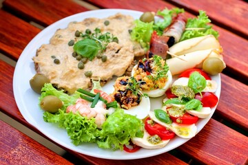 Teller mit Vitello Tonnato und Carpaccio und leckeren Häppchen auf einem Tisch