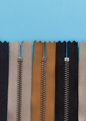 Black, yellow, grey zippers on a blue background. Top view. Copy space.