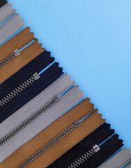 Collection of colored zippers on a blue background. Top view. Copy space.